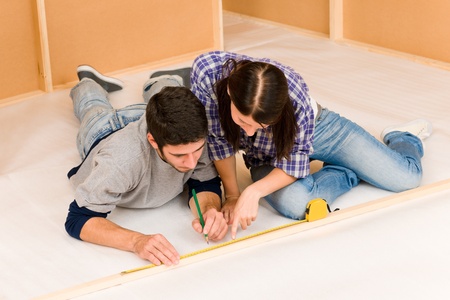 Home improvement young couple working on floor renovations measure ruleの写真素材