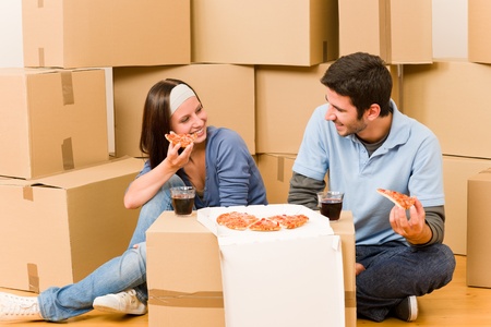 Moving into new home young happy couple eating pizzaの写真素材