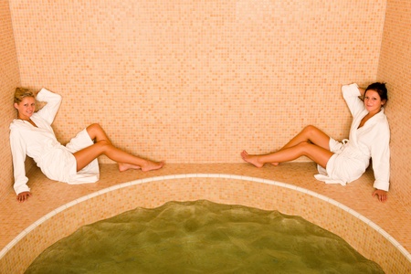 Relax bath spa two beautiful women sitting by water bathtubの写真素材