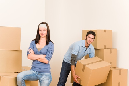 Happy young couple moving into new home carrying cardboard boxesの写真素材