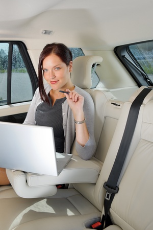 Executive woman manager working on laptop sitting car leather backseatの写真素材