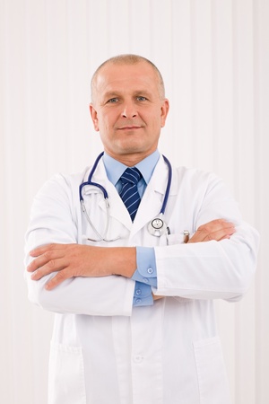 Portrait of mature professional doctor male with stethoscope crossed armsの写真素材