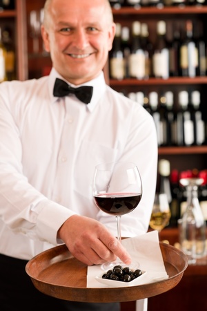 Wine bar waiter mature serving on tray glass olives restaurantの写真素材