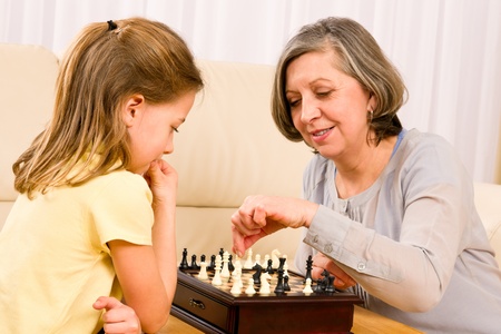 Grandmother and young girl playing chess together at homeの写真素材