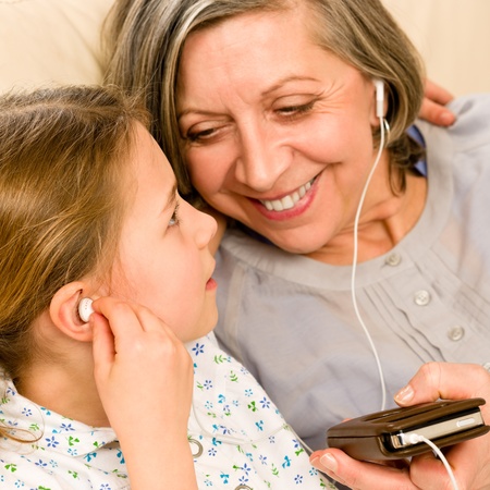 Granddaughter and grandmother listen to MP3 music headphones together smilingの写真素材