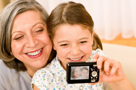 Grandmother and granddaughter take picture themselves smiling close-up portraitの写真素材