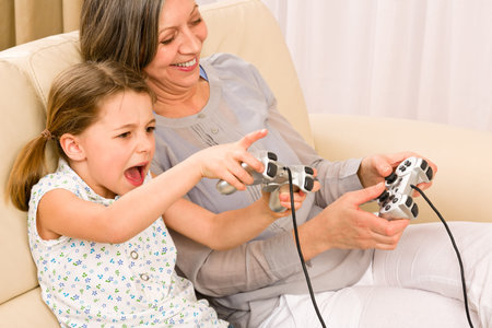 Grandmother play computer game with enthusiastic young girl have fun smiling