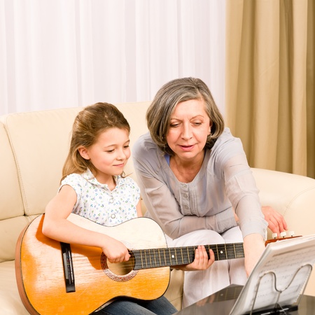 Young girl granddaughter sing play guitar to grandmother smileの写真素材