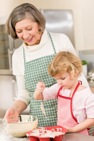 Woman and little girl make cupcakes together fill baking formの写真素材