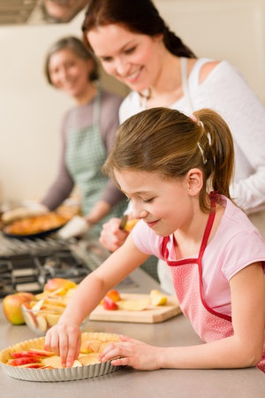 Young girl prepare apple tart baking with mother and grandmotherの写真素材