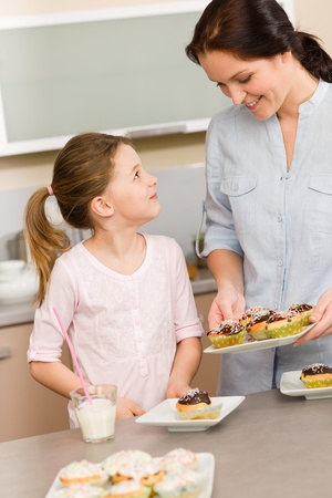 Little girl taste baked cupcakes with mum happy at homeの写真素材