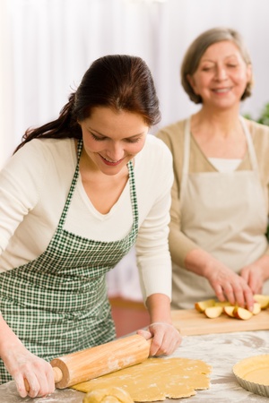 Happy woman making dough for apple pie grandmother drink wineの写真素材