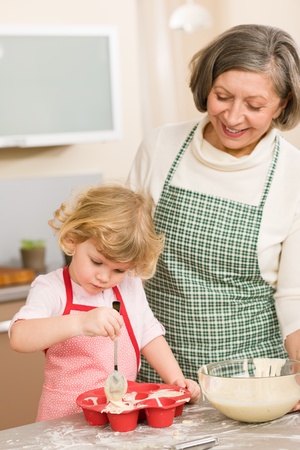 Woman and little girl make cupcakes together fill baking formの写真素材