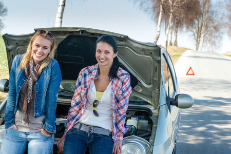 Car failure two young women waiting for help road assistance