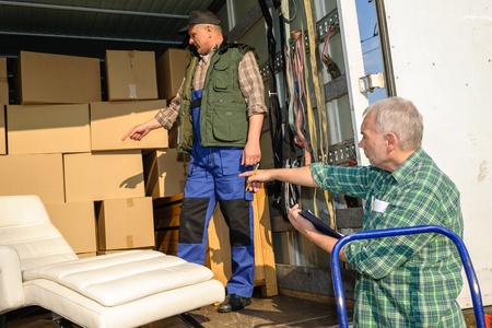 Two male movers unload furniture and boxes  from moving truckの写真素材