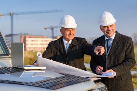 Male developers with blueprints at  construction site discuss architect projectの写真素材