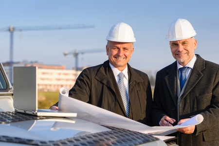 Male developers with blueprints at  construction site discuss architect projectの写真素材