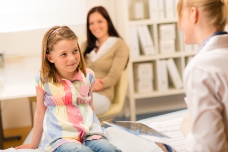 Little girl sitting on medical bed listening to pediatricianの写真素材