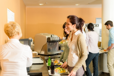 Cafeteria woman pay at cashier hold serving tray fresh foodの写真素材