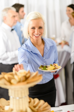 Smiling business woman during company lunch buffet hold salad plateの写真素材
