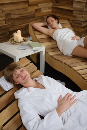 Two young women relaxing on wooden chair at luxury spaの写真素材