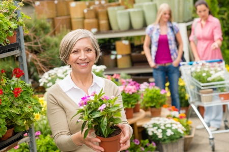 Senior lady shopping for flowers at garden centre smilingの写真素材