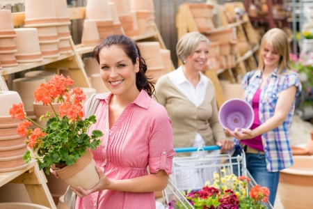 Young woman holding geranium in clay pot at garden centreの写真素材