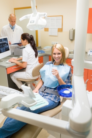Happy female patient at dental surgery dentist with assistantの写真素材