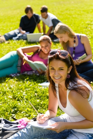 Students studying sitting on grass in park happy teens campusの写真素材