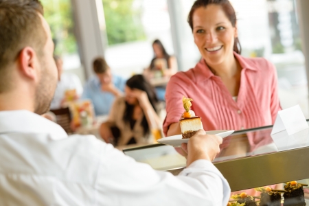 Waiter giving woman cake plate at cafe happy man serviceの写真素材