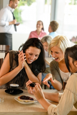 Friends looking at photographs and laughing cafe woman fun enjoyingの写真素材