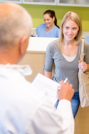 Male dentist calling next patient appointment for dental checkupの写真素材