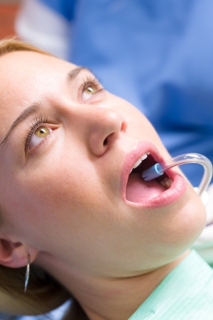 Woman patient at dentist open mouth with suction hose close-upの写真素材