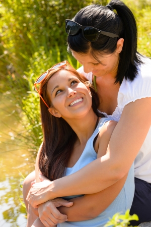Mother holding her teen daughter in arms hugging smiling outdoorsの写真素材