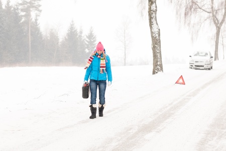 Woman carrying gas can snow car trouble winter breakdown walkingの写真素材