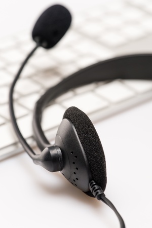 Office headphones with microphone over white keyboard on deskの写真素材