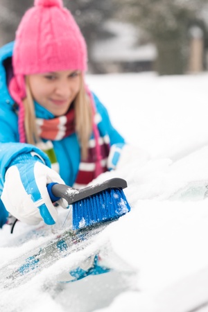 Woman wiping car windshield using brush snow winter happy workの写真素材