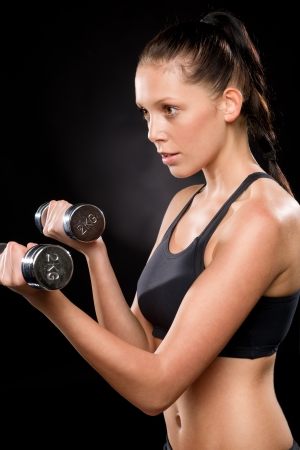 Half length of a young woman lifting dumbbells in sportswearの写真素材