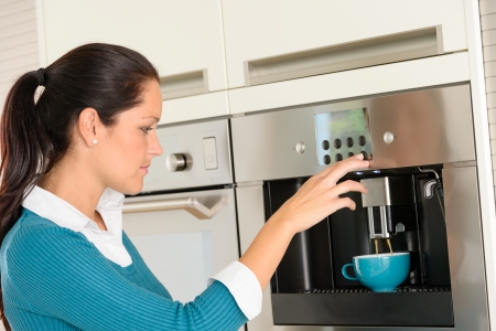 Happy young woman making coffee cup machine kitchen interiorの写真素材