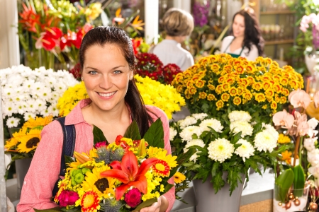Cheerful florist woman showing colorful flowers market shop retailの写真素材