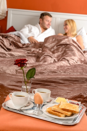 Happy married couple lying bed romantic breakfast hotelの写真素材