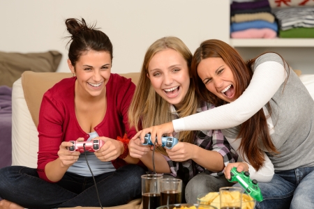 Laughing young girls playing with video games at homeの写真素材
