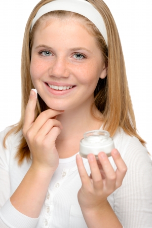 Cheerful young girl applying moisturizer face cream fingersの写真素材
