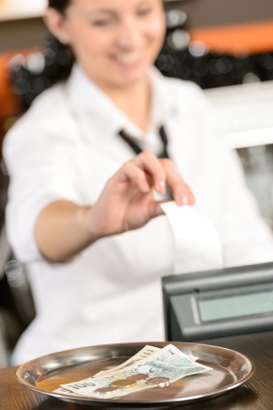Cash and young cashier giving receipt in bar CZKの写真素材