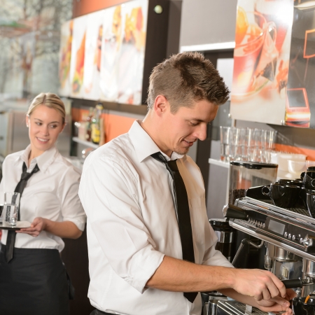 Young waiter and waitress working in bar serving coffeeの写真素材