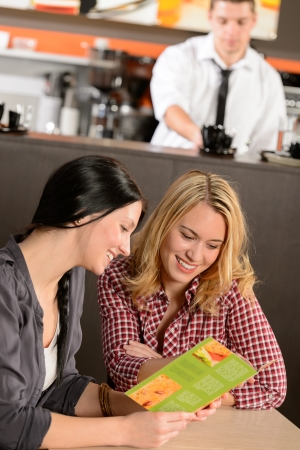 Two young female customers reading menu in pubの写真素材