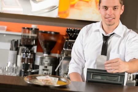 Handsome smiling male waiter giving receipt czech crowns in pubの写真素材