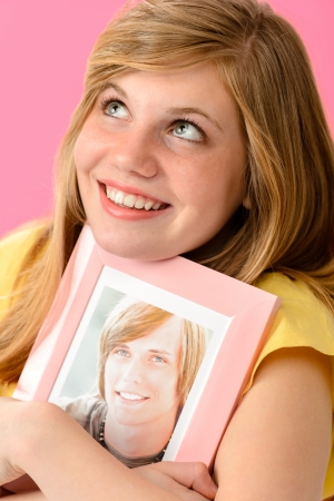 Joyful teenage girl embracing picture of her boyfriendの写真素材