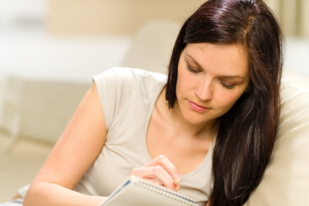 Young woman writing letter to copybookの写真素材