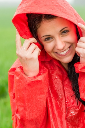 Portrait of cheerful teenager in the rain in red raincoatの写真素材